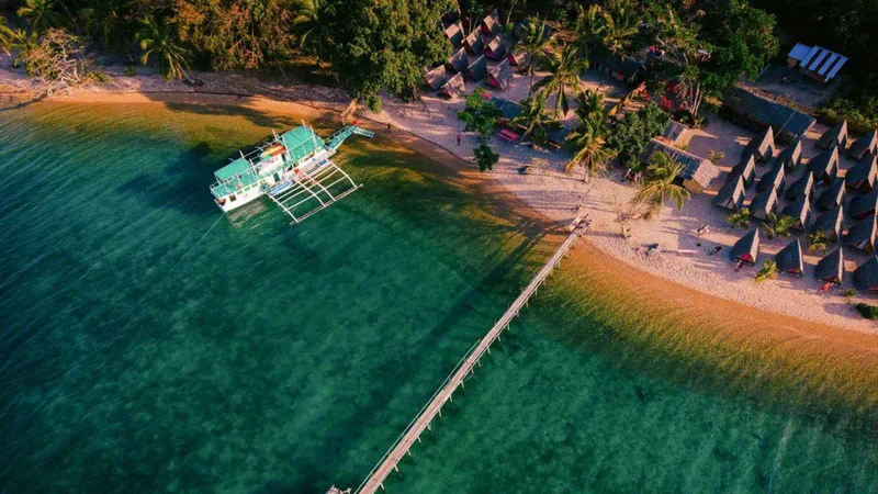 Outrigger expedition boat anchored off a remote island beach on a 3-day Coron to El Nido island hopping tour, Palawan, Philippines